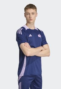 Námornícky modré športové tričko s svetloružovými akcentmi, s okrúhlym výstrihom, krátkymi rukávmi a bočnými panelovými detailmi. Zobrazené logo a emblém Adidas.