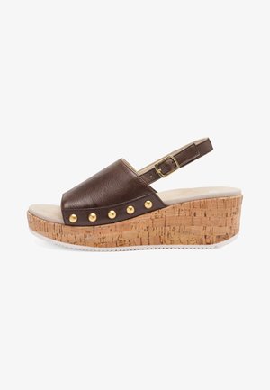 Brun læderkile sandal med korksål, guldfarvede nitter på siden og justerbar spænde rem ved hælen.