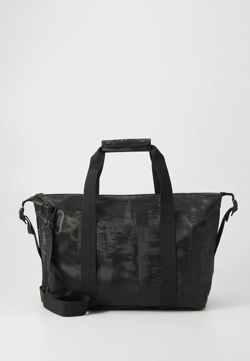 Svart duffelbag med en teksturert overflate, doble håndtak, justerbar skulderrem og glidelåslukking. Materialet er robust og vannavstøtende.