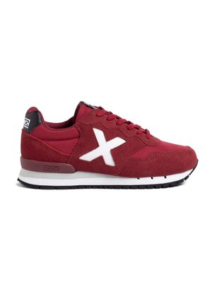 Zapatillas de ante rojo y malla con acentos blancos, que cuentan con un distintivo logo en forma de X, diseño de cordones y una pestaña en negro en una suela blanca y negra.