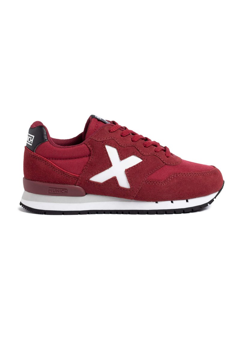 Zapatillas de ante rojo y malla con acentos blancos, que cuentan con un distintivo logo en forma de X, diseño de cordones y una pestaña en negro en una suela blanca y negra.