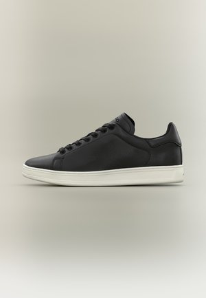 Zwarte leren lage sneaker met zwarte veters en een witte rubberen zool, zijaanzicht op een neutrale achtergrond.