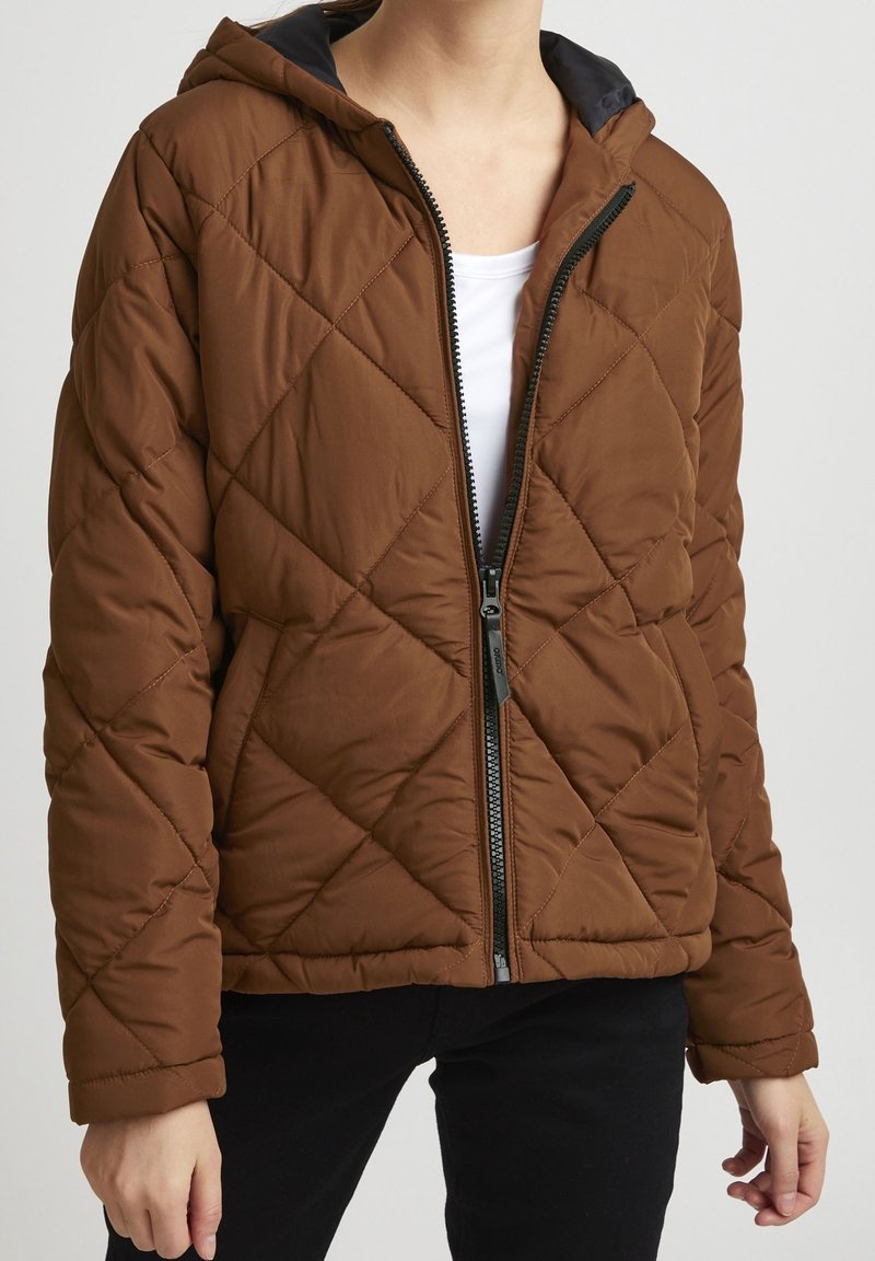 Veste matelassée marron avec capuche, dotée d'une fermeture éclair frontale et d'une doublure noire. Fabriquée en tissu lisse, conçue pour la chaleur et le confort.