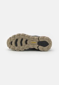 Black athletic shoe sole with deep, rugged treads; features Goodyear branding and a contrasting beige rubber base for traction.