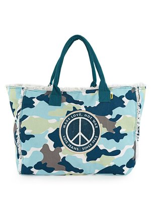 Bolsa de tote con estampado de camuflaje en azul claro, verde y gris, con flecos decorativos y un parche central en forma de símbolo de paz con texto. Material de algodón.