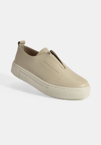 Beige instappers met een gestructureerd leren bovenwerk, elastische vamp en een dikke rubberen zool met een gestructureerd grippatroon.