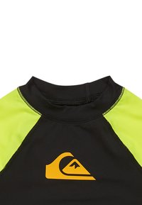 Czarna koszulka ochronna z krótkim rękawem, z jasnymi żółtymi akcentami i pomarańczowym logo. Gładka tekstura z kontrastowymi szwami.