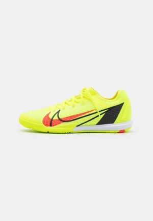 Chaussure de course jaune vif avec un design swoosh rouge et noir, semelle blanche et coupe basse à la cheville sur fond blanc uni.