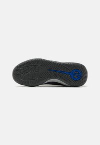 Suela de zapato atlético negro con patrón de agarre texturizado. Presenta un destacado logo de acento azul y un borde de goma gris.