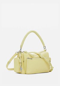 Mała żółta torebka z wieloma zapinanymi na zamek przegrodami, skręconym uchwytem u góry, regulowanym paskiem na ramię oraz dekoracyjnymi węzłami.