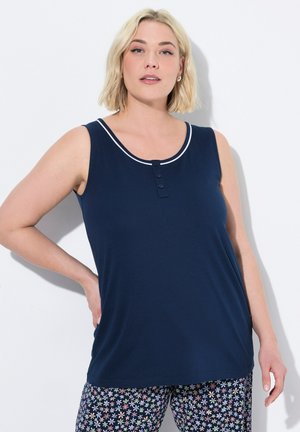 Top senza maniche blu navy in morbido tessuto con bordo bianco, caratterizzato da tre bottoni scuri sul colletto. Abbinato a pantaloni da pigiama a fiori con motivo.