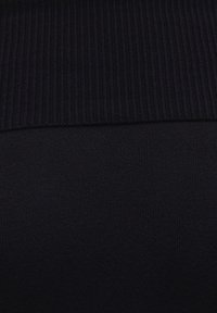 Schwarzer, gerippter Strickstoff mit glatter Textur, der oben ein dickeres Rippband und darunter ein weicheres Strickmuster aufweist.