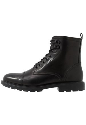 Zwarte leren veterschoenen voor enkels met cap-toe, metalen oogjes, trek-lusje bij de hiel en dikke, getextureerde rubberen zool.