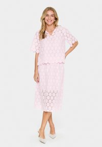Lace two-piece set in light pink, featuring a scalloped hem, short sleeves, and a midi-length skirt with overlapping floral patterns.