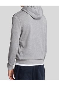 Grå hoodie med dragsko i huven, ribbade manschetter och nederkant, mjuk textur och enkel design, bärs över en vit skjorta.