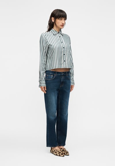 Ριγέ, κοντομάνικο πουκάμισο με κουμπιά σε τυρκουάζ και λευκό, συνδυασμένο με σκούρα μπλε τζιν κανονικής γραμμής και παπούτσια με λεοπάρ σχέδιο.