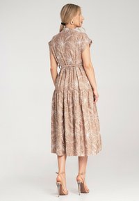 Maxikleid in Hellbraun mit weißem botanischem Druck, elastischer Taille, kurzen Ärmeln und gestuftem Rock; glattes Material mit leichtem Glanz.