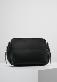 Czarna skórzana torebka o gładkim wykończeniu, zaokrąglonym kształcie, złotym okuciu, bocznych zamkach błyskawicznych oraz płaskiej podstawie zapewniającej stabilność.