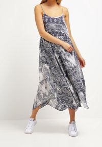Maxime dress in tummansininen ja valkoinen geometrisin ja abstraktein kuviomin, kevyt kangas, spaghetti-hihnat ja sivuhalkiot.