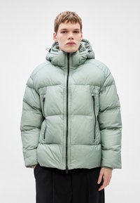 Μπου�φάν με επένδυση σε ανοιχτό πράσινο χρώμα με κλείσιμο σε φερμουάρ, ψηλό γιακά και κουκούλα. Διαθέτει πλαϊνές τσέπες με φερμουάρ και υφασμάτινες υφές στις επιφάνειες.