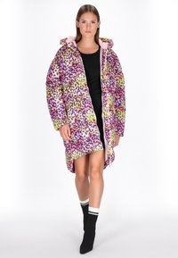 Cappotto puffer colorato e oversize con una stampa leopardata rosa, gialla e verde. Presenta una chiusura con zipper e un cappuccio. Texture morbida e design imbottito.