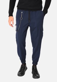 Pantaloni jogger blu navy in tessuto leggero, con polsini elastici, tasche laterali e dettaglio a catena con clip e portachiavi.