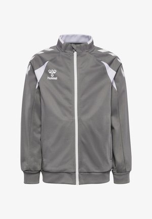 Veste de sport grise zippée avec des accents blancs sur les épaules, une fermeture éclair blanche, des poignets côtelés et le logo hummel sur le côté gauche de la poitrine.