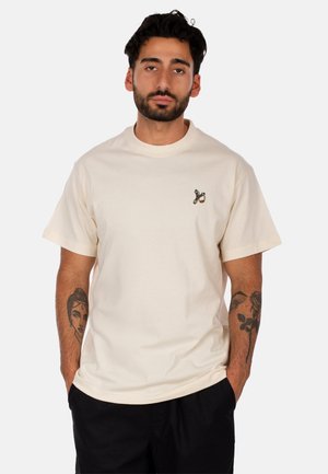 Cremfarbendes Baumwoll-T-Shirt mit kurzen Ärmeln, einem Rundhalsausschnitt und einem kleinen grafischen Design auf der linken Brustseite. Entspanntes Schnitt.
