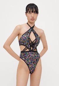 Multikleurige pailletten zwemkleding met een halternekontwerp, uitsparingen en zwarte banden. De stof is glanzend met een textuurfinish.