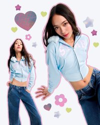 Sweatshirt azul curto com capuz felpudo, texto em lantejoulas "ESTRELA", combinado com jeans de perna larga. O fundo inclui formas geométricas coloridas.