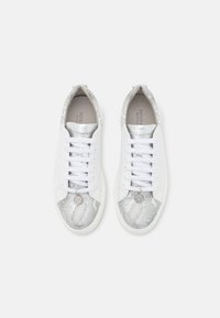 Sneaker bianche in pelle con accenti in pelle a motivo serpente metallico, dotate di lacci bianchi, suole interne perforate e un charm decorativo in metallo.