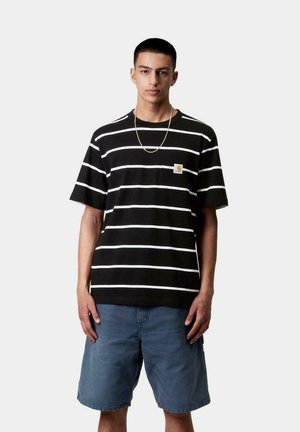 Camiseta de manga corta a rayas negras con rayas horizontales blancas y un logo en el pecho, combinada con pantalones cortos de mezclilla. La tela parece suave.
