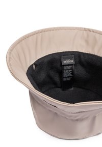 Bucket-Hut in hellem Beige, aus glattem Polyester, mit einem weichen schwarzen Fleece-Futter und einem eingenähten Etikett innen.