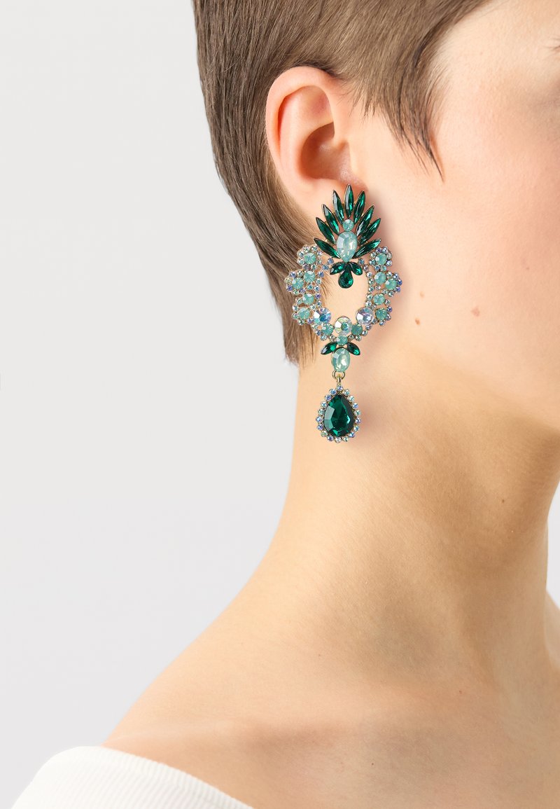 Green gemstone earrings featuring a floral design with multiple shapes, including teardrop and round stones, set in a metallic frame.