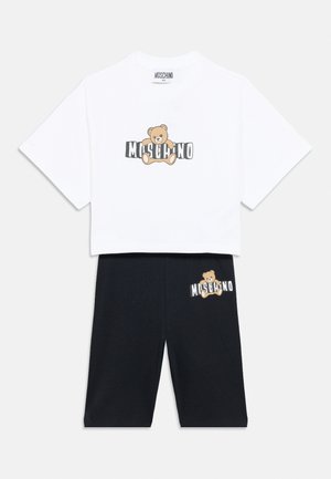 Witte cropped top met korte mouwen en zwarte knielange shorts, elk bedrukt met een teddybeer en het "MOSCHINO"-logo.
