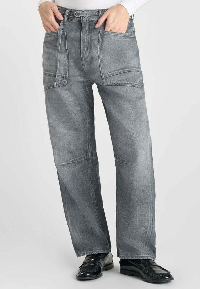 Pantalons en denim gris avec une coupe décontractée, dotés de plusieurs poches, d'une taille à passants de ceinture et d'une texture lisse. Des chaussures noires complètent la tenue.