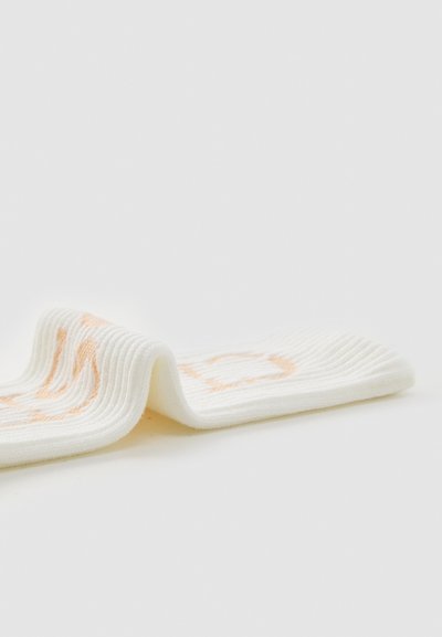 Biele rebrované ponožky s oranžovým geometrickým vzorom. Mäkka textura, flexibilný tvar, vhodné na bežné nosenie alebo šport.