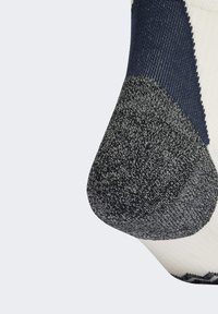 Detailný záber na pätu pletenej ponožky v námorníckej, čiernej a bielej farbe, ktorá ukazuje textúrované šitie a vystužený materiál.