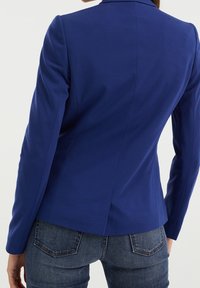 Blå skräddarsydd kavaj med en mjuk textur, enkel vent bak, och skräddarsydda ärmar. Kompletteras med mörka denimjeans.