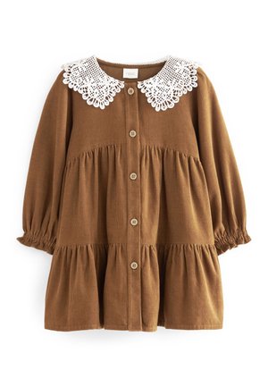 Brązowa sukienka z sztruksu z białym koronkowym kołnierzykiem, zapinana na guziki z przodu, z marszczonymi rękawami zakończonymi elastycznymi mankietami. Sukienka o wielowarstwowej konstrukcji z falbanką u dołu.