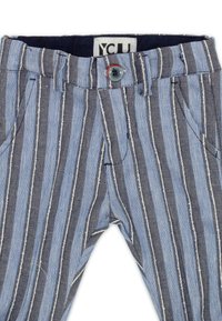 Pantaloni a righe blu e blu navy realizzati in tessuto testurizzato, con chiusura frontale a bottone, tasche e strisce bianche a contrasto.