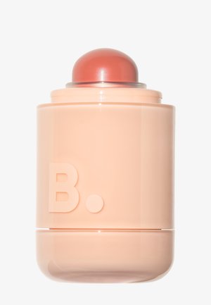 Conteneur cylindrique de couleur pêche avec un "B." en relief et un couvercle corail arrondi sur un fond blanc.