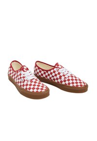 Baskets en toile à carreaux rouges et blancs avec semelles en caoutchouc marron, présentant des lacets blancs et un design bas.