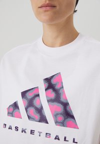 Hvid bomulds t-shirt med et stort leopard-mønstret grafisk motiv i lilla og lyserød, med "BASKETBALL" trykt nedenfor med store bogstaver.
