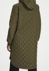 Manteau long matelassé vert olive avec capuche, présentant un motif losange et des poignets côtelés, conçu pour la chaleur et la couverture.