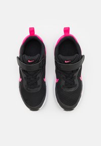 Scarpe da ginnastica nere con accenti rosa, dotate di una tomaia in mesh, colletto imbottito e una cintura in Velcro. La suola è bianca con grip testurizzato.