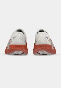 Valkoiset ja punaiset urheilukengät, joissa on teksturoitu verkkomateriaali päällisosassa, pehmustettu kaulus ja erottuva pito-pohja, jossa energiaFOAM-brändäys.