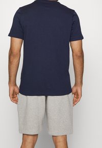 Marineblå t-shirt med kort ärm och rundad halsringning samt grå shorts. Tyget ser slätt ut, med en avslappnad passform och inga synliga mönster eller detaljer.