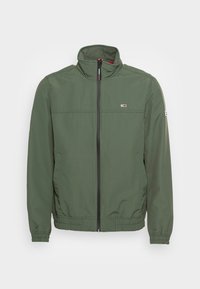 Grön lättviktsjacka med hög krage, hel dragkedja, elastiska mudd och en liten logga på bröstet. Mjukt, hållbart tyg.