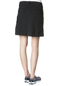 Czarna spódnica z dopasowaną talią, tylnymi kieszeniami i dołem sięgającym powyżej kolan. W zestawieniu z czarnymi sportowymi butami z siateczkowym wzorem.